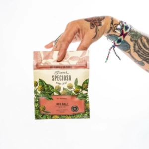 Red Bali Kratom Powder in a 20g bag held by hand with tattoos.